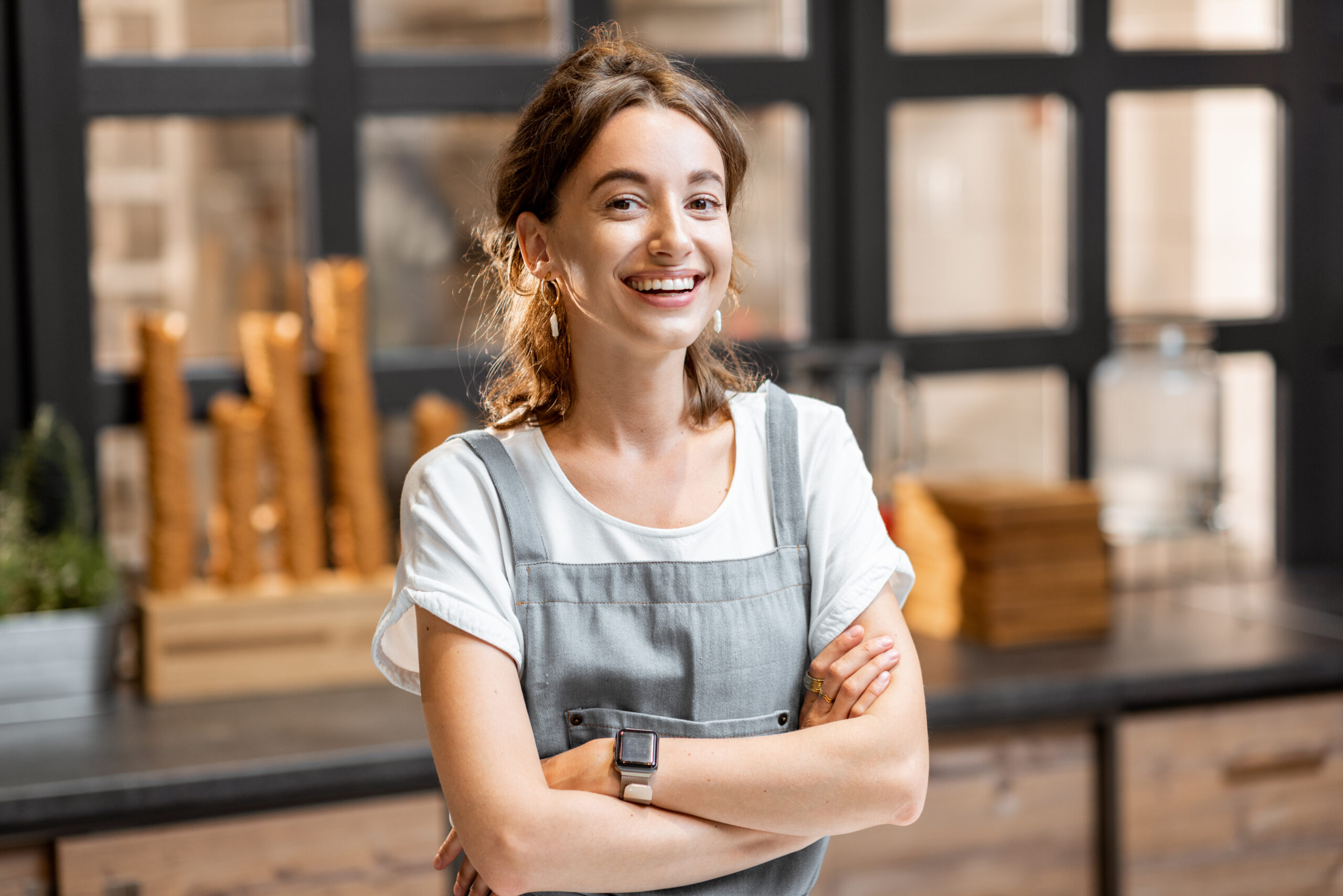 Portrait of a young and happy saleswoman at the counter in ice cream shop or cafe. Concept of a small business and retail